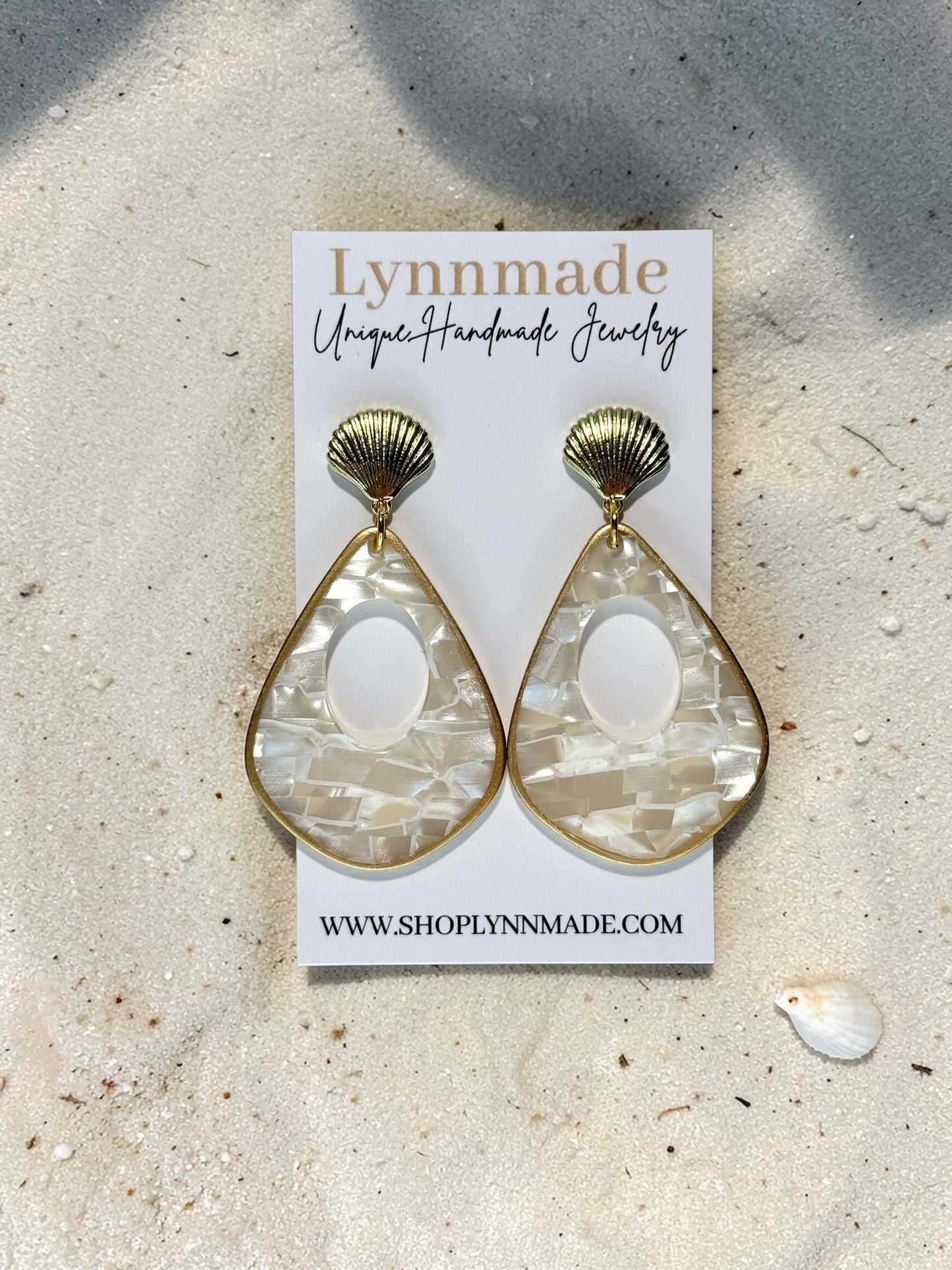 Luminous Tide Mother of Pearl Shell Drop Earrings in Gold or Silver on white silk and sand background.