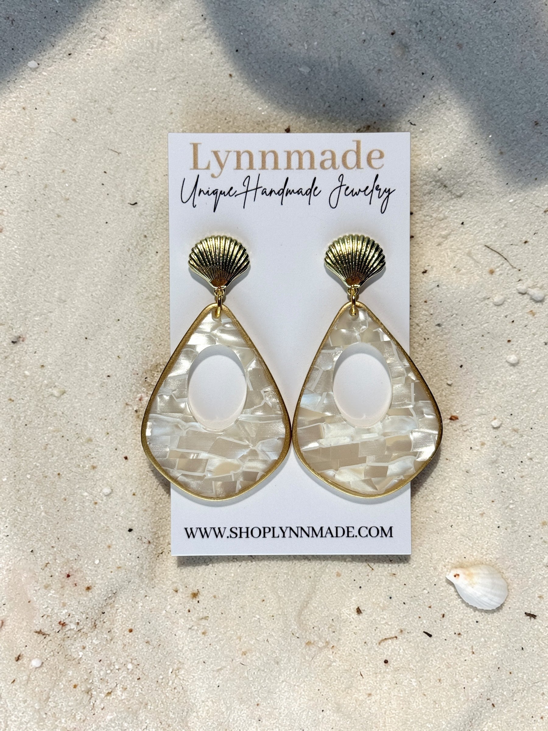Luminous Tide Mother of Pearl Shell Drop Earrings in Gold or Silver on white silk and sand background.