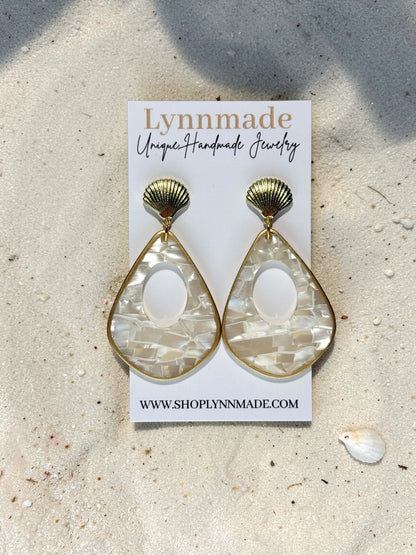 Luminous Tide Mother of Pearl Shell Drop Earrings in Gold or Silver on white silk and sand background.
