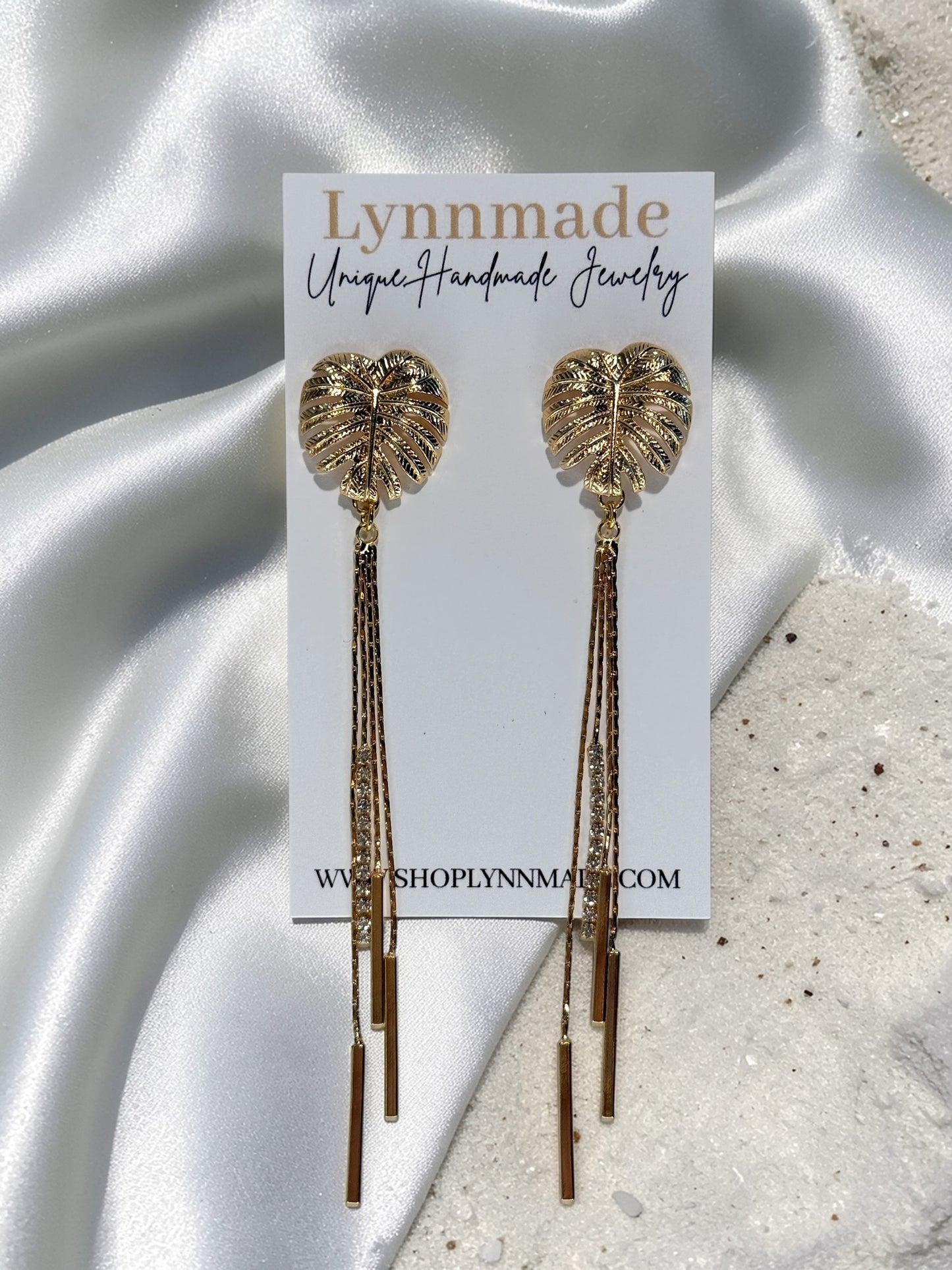 Pair of gold Long Monstera Tassel Earrings with textured leaf studs and shimmering chain fringe. Lynnmade Jewelry 