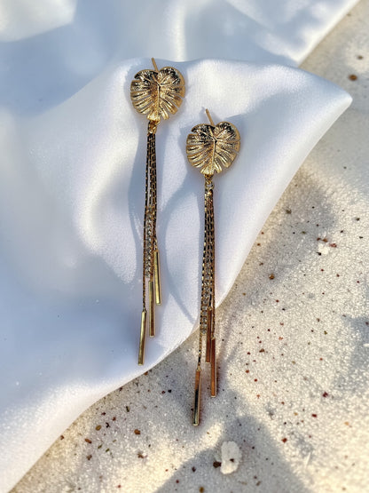 Pair of gold Long Monstera Tassel Earrings with textured leaf studs and shimmering chain fringe.