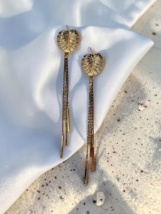 Pair of gold Long Monstera Tassel Earrings with textured leaf studs and shimmering chain fringe.