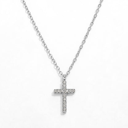 A close-up view of a dainty 14k gold-plated tiny cross necklace, featuring a delicate yellow gold chain and a petite cross pendant closely set with sparkling cubic zirconia (CZ) diamonds, shown as a fine jewelry product display and worn on a model.
