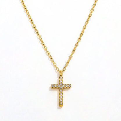 A close-up view of a dainty 14k gold-plated tiny cross necklace, featuring a delicate yellow gold chain and a petite cross pendant closely set with sparkling cubic zirconia (CZ) diamonds, shown as a fine jewelry product display and worn on a model.